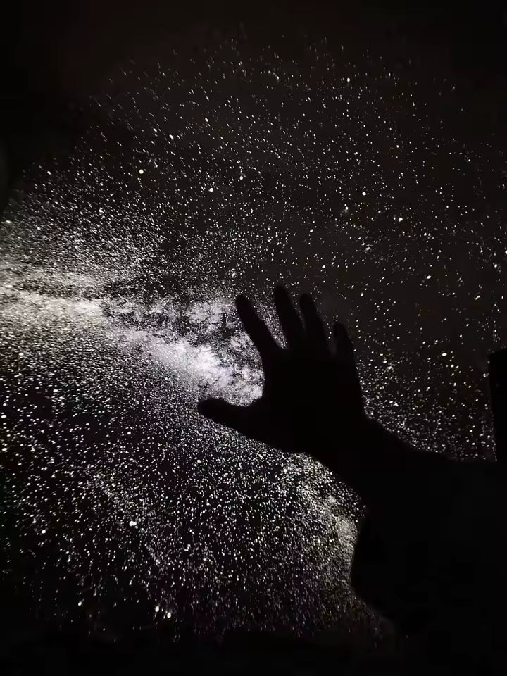 Mano tocando la proyección de estrellas en la pared